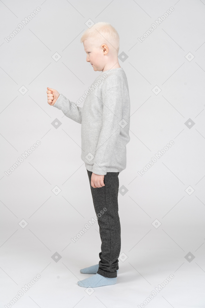 Маленький мальчик стоит с поднятым кулаком