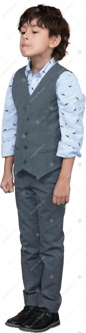 Front view of a boy in suit standing still and making faces