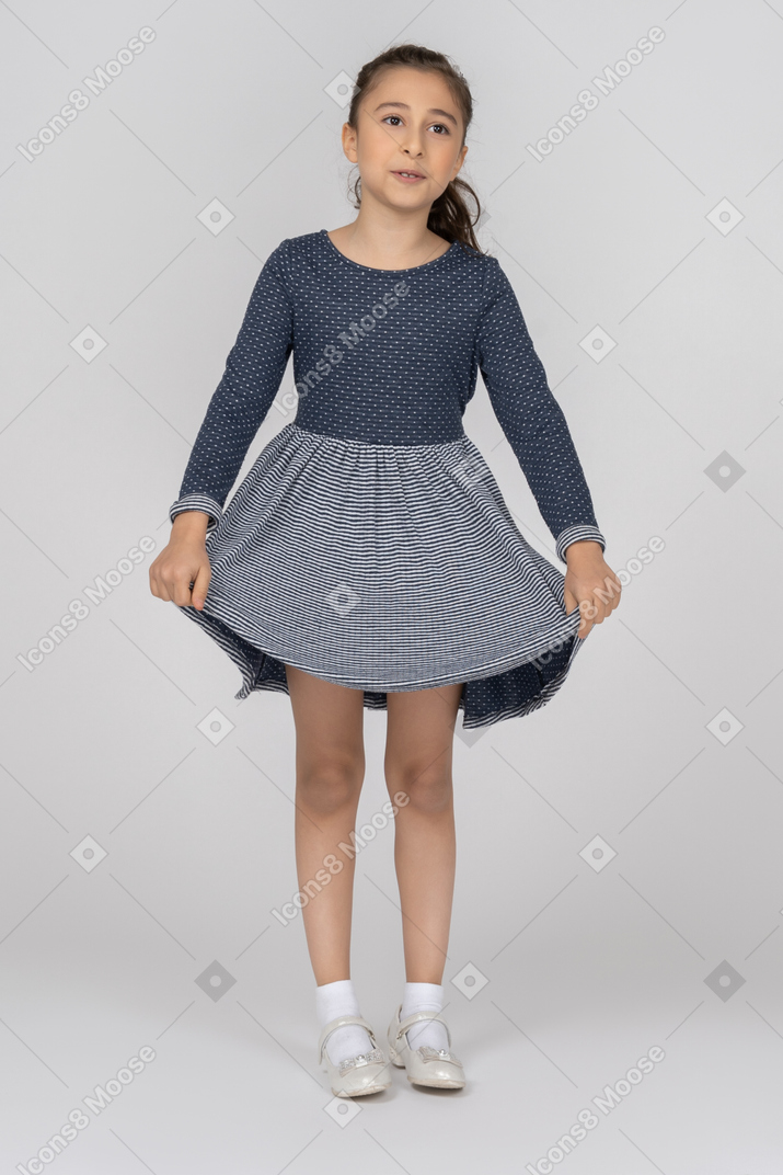 Front view of a girl holding the hem of her skirt