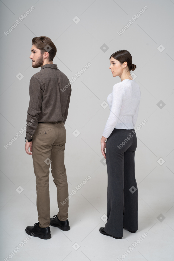 Three-quarter back view of a young couple in office clothing pressing lips