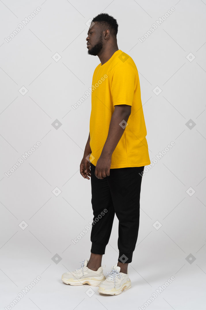 Three-quarter view of a tired unwilling young dark-skinned man in yellow t-shirt