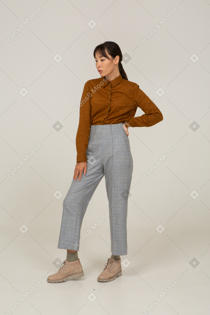 Three-quarter view of a young asian female in breeches and blouse putting hand on hip
