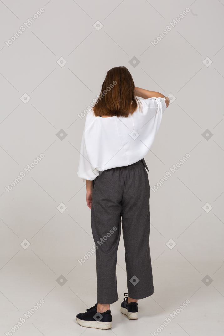 Back view of a young lady in office clothing touching forehead