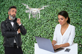 Hombre con un dron de reparto junto a una mujer que trabaja