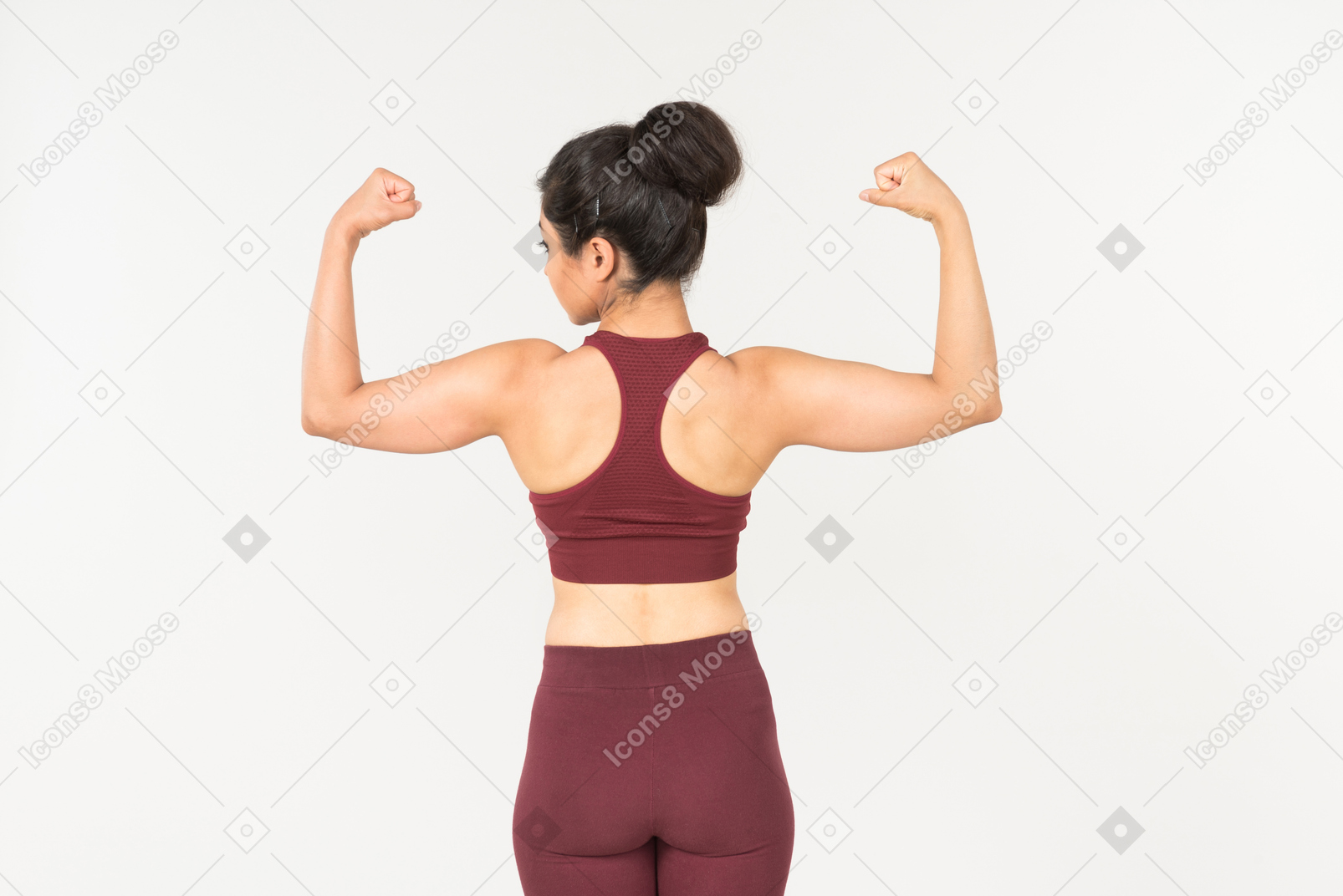 Молодая индийская женщина в спортивной одежде, показывая мышцы и стоя спиной к камере