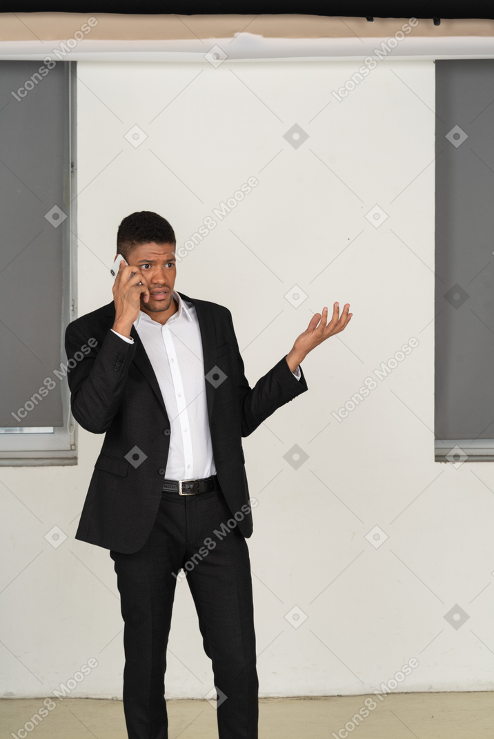 A good looking guy dressed in the black suit and talking to the phone