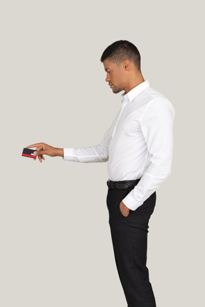 Man in white shirt and black pants holding a credit card