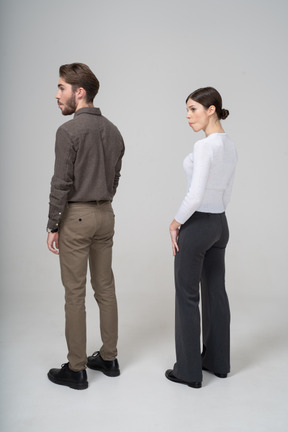 Three-quarter back view of a young couple in office clothing tucking cheeks in