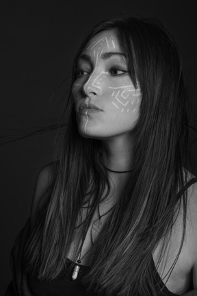 Retrato noir de tres cuartos de una mujer joven con arte facial étnico