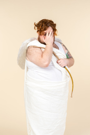Big guy dressed as a cupid seems to be ashamed of something