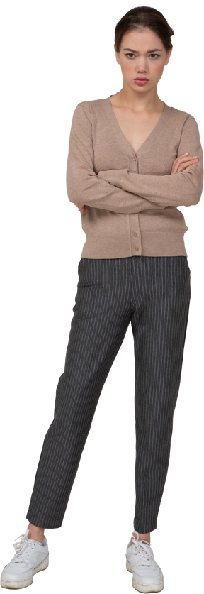Vista frontal de una joven ofendida en jersey y pantalones cruzando las manos