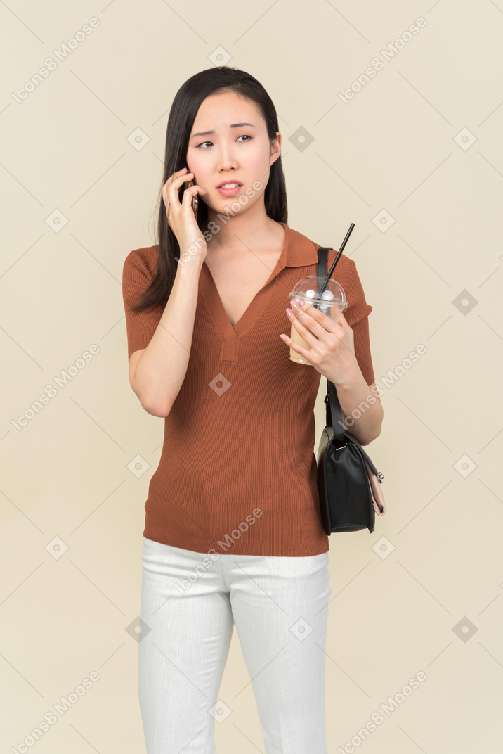 Confused young asian girl talking on the phone