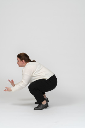 Side view of a plump woman in casual clothes squatting