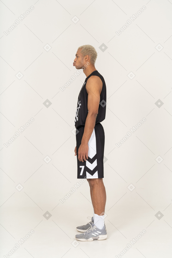 站着不动的撅嘴的年轻男篮球运动员的侧视图