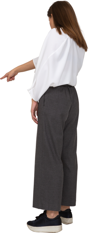 Vista posteriore di tre quarti di una giovane donna in abiti da ufficio che punta il dito