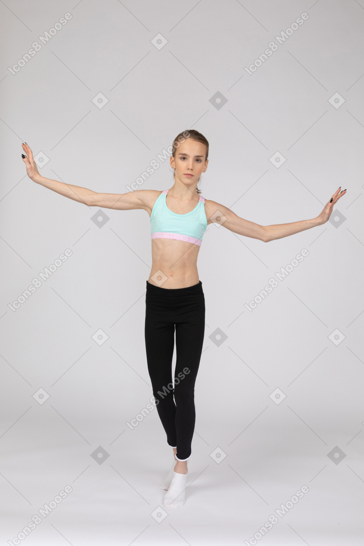 一个青少年的女孩，穿着运动服，tip起脚尖的前视图