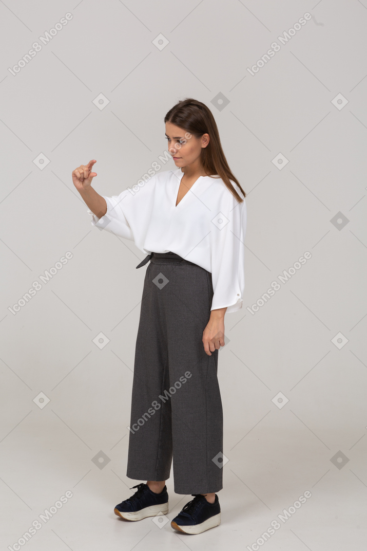 Vista di tre quarti di una giovane donna in abiti da ufficio che mostra una taglia di qualcosa