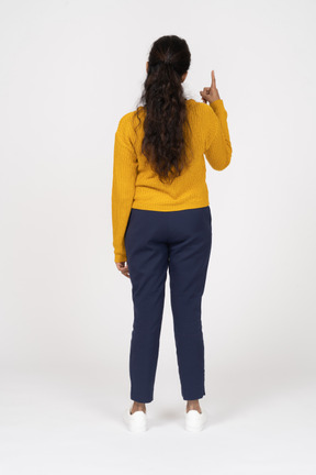 Vista traseira de uma garota com roupas casuais apontando para cima com um dedo