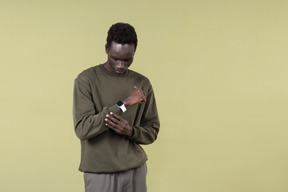 Giovane uomo di colore che indossa abiti casual, con airpods e smartwatch nel corso del suo allenamento