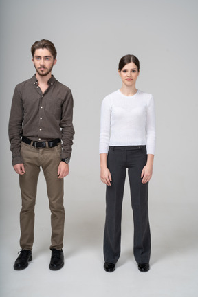 Front view of a young couple in office clothing standing still