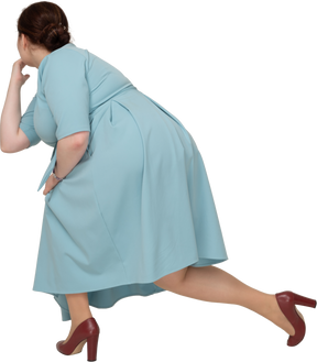 Rear view of a woman in blue dress squatting