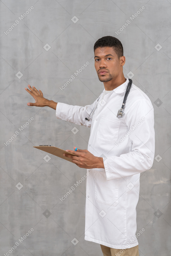 Médico varón sosteniendo portapapeles y explicando algo