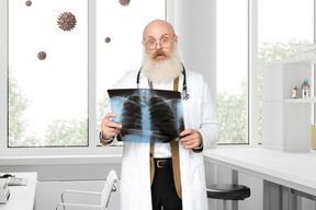 Médico velho chocado segurando um raio-x