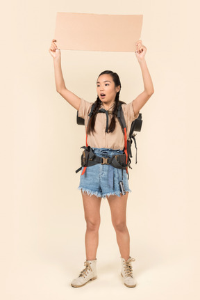 Young female hitchhiker holding up paper card