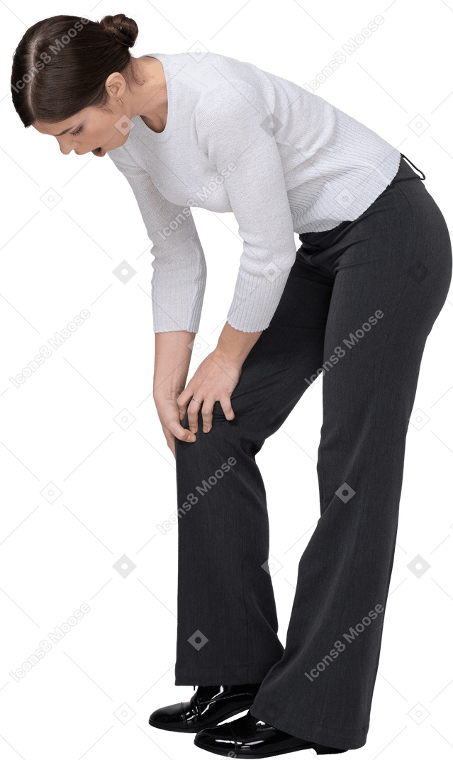 Вид сбоку молодой женщины в офисной одежде, касающейся колена
