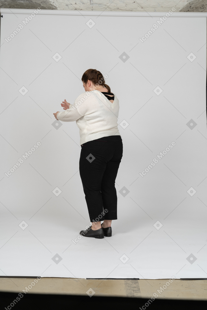 Vista lateral de uma mulher gorda com um suéter branco gesticulando