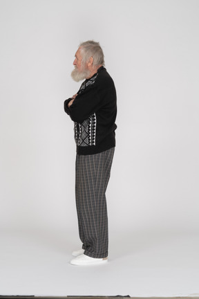 Side view of elderly man standing with arms crossed