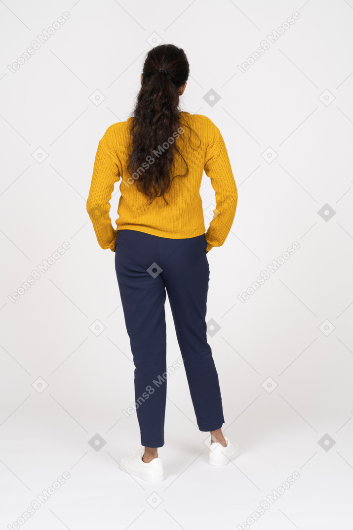 Rear view of a girl in casual clothes posing with hands in pockets