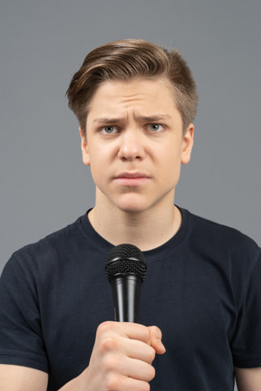 Jeune homme sérieux à l'aide d'un microphone