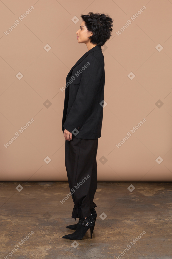 Vista lateral de una mujer de negocios en un traje negro mostrando la lengua