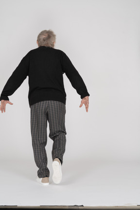 Anciano caminando con los brazos extendidos hacia atrás