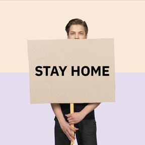 Man standing with a sign saying stay home in hands