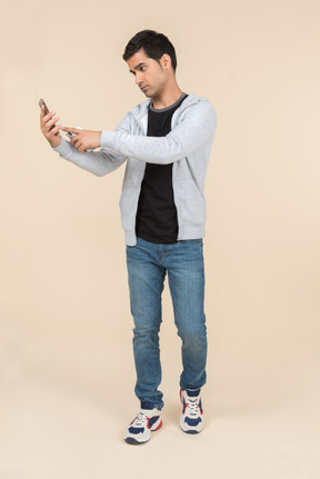 Junger kaukasischer mann, der ein smartphone anhält und auf einem anderen schaut