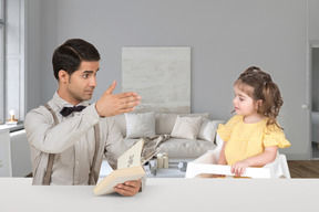A man reading to a little girl at a table