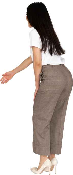 Side view of a young lady in breeches and t-shirt outstretching her hand and bending down