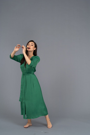 Vista di tre quarti di una giovane donna in abito verde che suona il flauto
