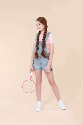 Optimistic teenage girl holding tennis racket