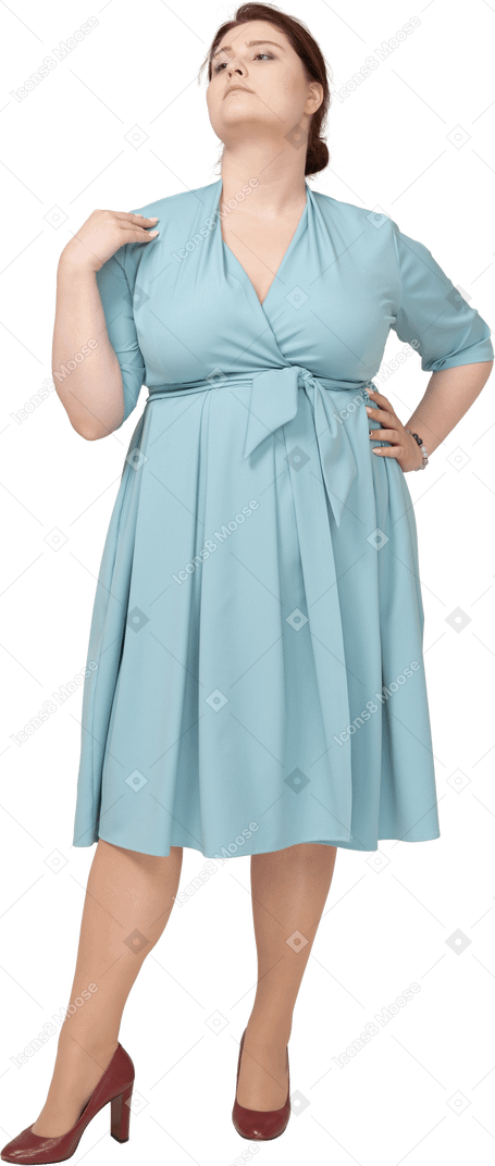 Vista frontal de uma mulher de vestido azul posando com a mão no quadril