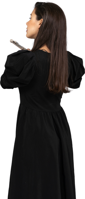 Back view of a young lady in black dress holding flute