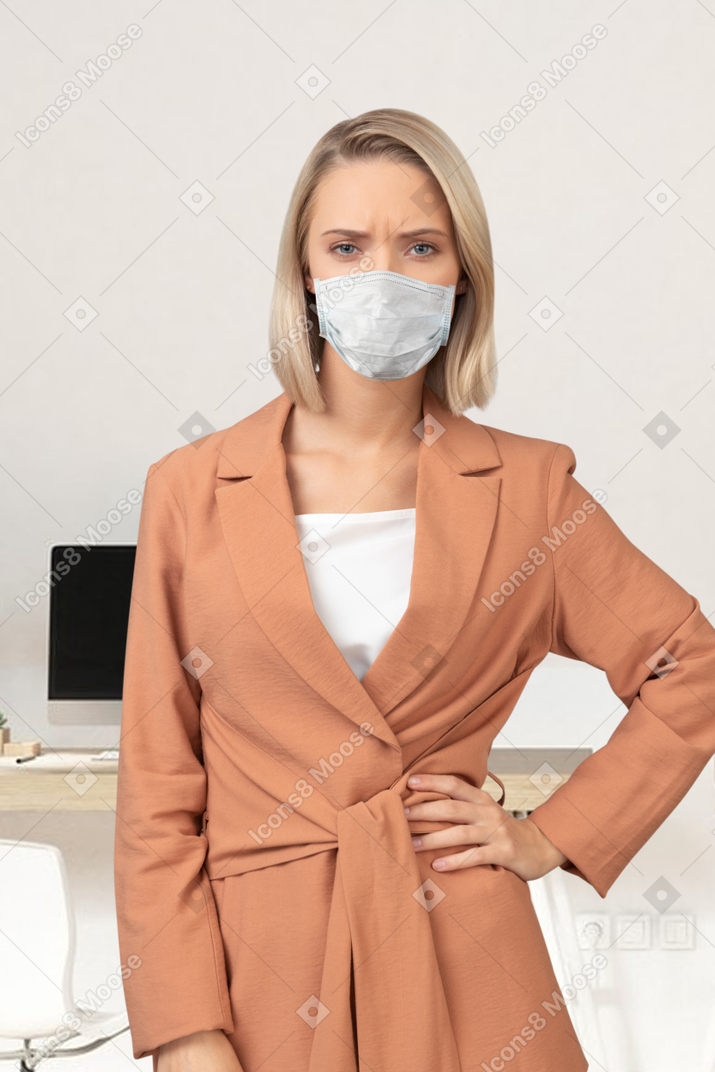 A woman wearing a face mask standing in front of a desk