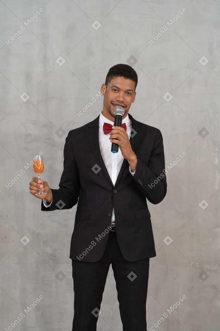 Man holding glass and mic and looking at camera