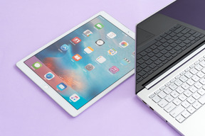 Laptop and digital tablet over lilac background