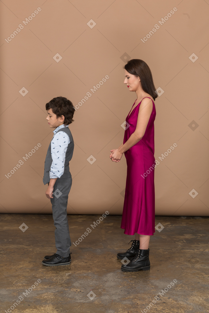 Mujer joven en vestido rojo y niño parado quieto