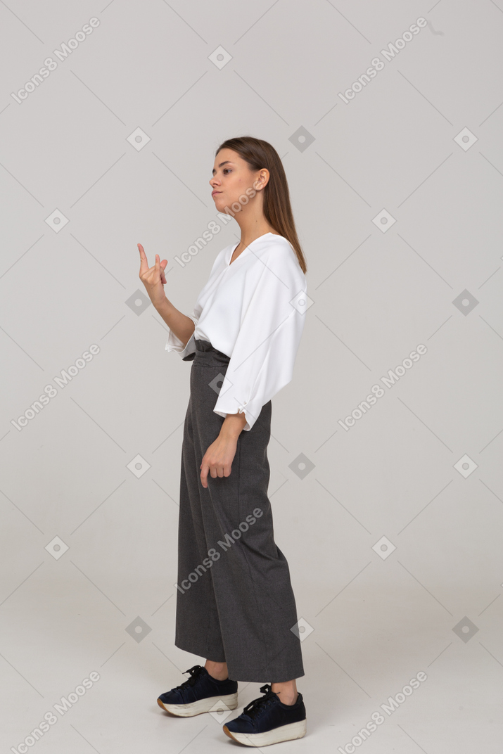 Three-quarter view of a young lady in office clothing showing rock gesture