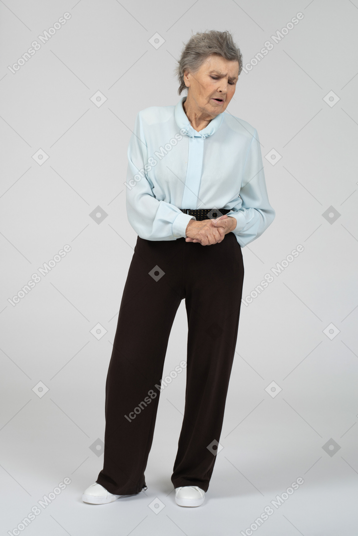 Vista frontal de una anciana suspirando con las manos entrelazadas