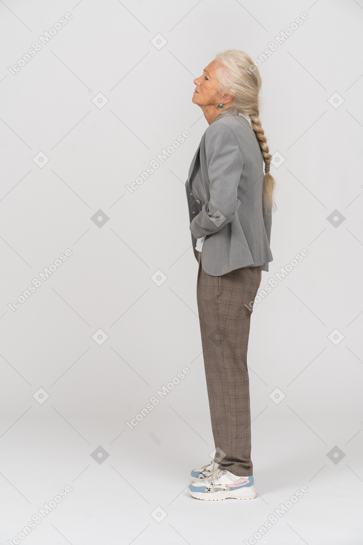 Vista lateral de una anciana en traje que sufre de dolor de estómago
